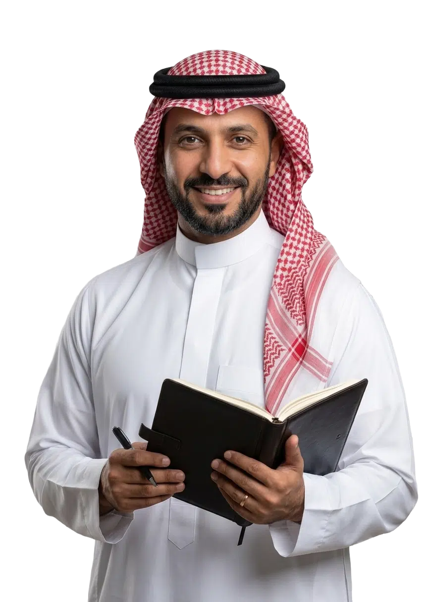 A smiling man in a white thobe and red shemagh holding a notebook and pen